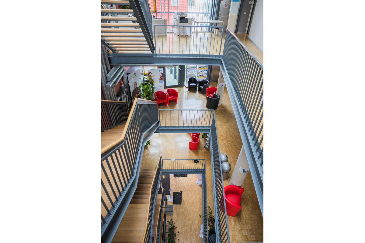 Das Bild zeigt eine Innenansicht der DAA Fachschule für Sozialpädagogik Aalen. Zu sehen sind das Treppenhaus über mehrere Stockwerke, das Foyer, sowie Sitzecken.
